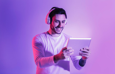 Wall Mural - Handsome man with tablet and wireless headphones