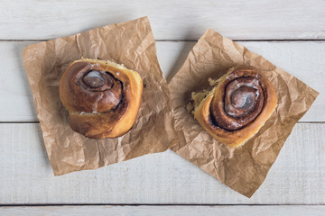 Two cinnamon rolls ready to eat over a white rustic wooden table. Top view