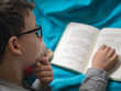 © Daniel CHETRONI - Little child, 8 years old boy reading a book at home with his toy teddy bear
