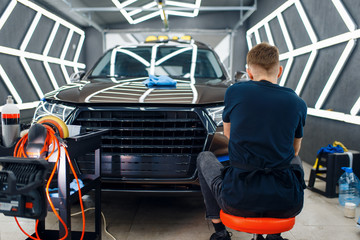 Wall Mural - Male worker polishes car surface, detailing