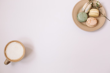 Wall Mural - Homemade colorful macarons on the brown plate on the white background.Cup of coffee.Blossom.