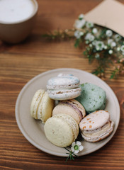 Wall Mural - Colorful homemade macarons are lying on the brown wooden background.Cup of coffee. 