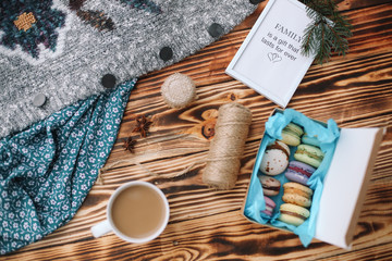 Wall Mural - Homemade colorful macaroons in the box are lying on the brown wooden table with cup of coffee and picture Family is a gift that lasts forever. Cup of coffee. Anise, honey and colorful tissue.