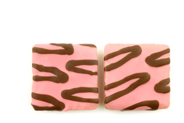 Wall Mural - freshly baked square pink glazed cakes with chocolate dressing on a white background