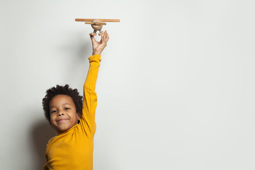 Wall Mural - Little black child boy with plane model on white background