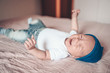 © Алина Троева - Cute crying little baby boy lying on pink blanket at bedroom. Newborn. Baby stays awake on the bed. Closeup portrait of emotional newborn baby in blue jeans, blue cap, and white t-shirt
