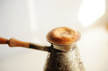 Brewing Turkish Coffee In Cooper Cezve. High Rising Foam Close Up. White Background