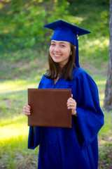 Portrait of attractive young woman in cap and gown after graduation in 2020