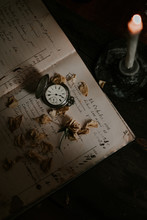 Petals Of Dried Rose And Vintage Pocket Watch Placed On Shabby Page Of Aged Diary With Memories