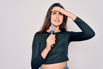 Sticker - Young beautiful singer performer girl singing using music microphone over isolated background stressed with hand on head, shocked with shame and surprise face, angry and frustrated. Fear and upset 