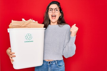 Poster - Young beautiful woman holding recycle cardboard containter recycling for eco environment screaming proud and celebrating victory and success very excited, cheering emotion