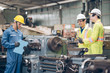 © iStocker - Three technician inspecting complex metal component at machine in factory