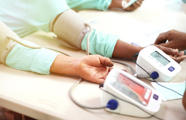 close up doctor using sphygmomameter checking blood pressure to a female patient in the hospital. Blood pressure measurement.  Blood pressure monitor. Heartbeat check. Blood pressure check. 