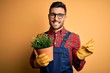 Young gardener man wearing working apron gardening plat for hobby over yellow background very happy pointing with hand and finger to the side