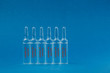 © Oleksii Halutva - Medicine in an ampoule on a blue background.