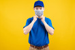 © Kiattisak - Delivery handsome man wearing mask for ready protect delivery to front home receiver shipping deliver cargo prevention infected virus on yellow background isolated studio shot, copy space.