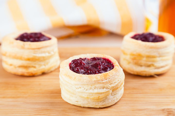 Danish pastry cake with cranberry jam and fresh blueberry and raspberry on the table. Sunny breakfast.