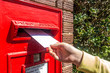 © Matthew Ashmore - A child's hand posting a letter into a post box embedded into a brick pillar.