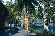 Back view: Beautiful blonde girl with perfect butt posing on the luxury hotel resort  with wonderful pools and palm trees