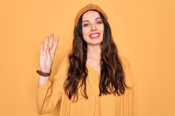 Wall Mural - Young beautiful woman wearing casual t-shirt and diadem standing over yellow background showing and pointing up with fingers number four while smiling confident and happy.