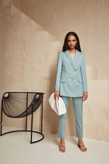 Beautiful brunette woman natural make up wear fashion clothes casual dress code office style blue jacket and pants suit for romantic date business meeting accessory bag interior boho stairs flowerpot.