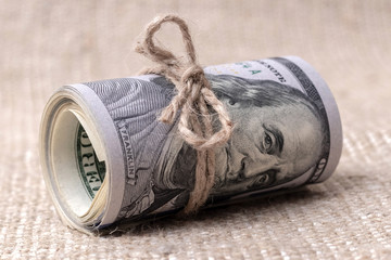 Money (US dollars) in a roll tied with a rope, US dollars in a roll