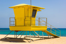 Bright Yellow Lifeguard Station Off Duty On Empty Beach In Corralejo Natural Park, Fuerteventura. Baywatch Tower With Nobody On Turquoise Water Ocean On Sunny Day. Summer Holidays Concept