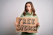 © Krakenimages.com - Young blonde girl holding protest banner with free speech message as rights freedom scared in shock with a surprise face, afraid and excited with fear expression