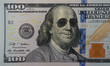 Happy smiling president Franklin portrait wearing sunglasses on 100 dollar bill. Concept of economic growth