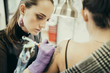 © Westend61 - female tattooist tattooing upper arm of female customer