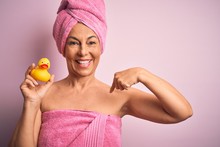 Middle Age Woman Wearing Pink Bath Towel From Beauty Body Care Holding Rubber Yellow Duck With Surprise Face Pointing Finger To Himself