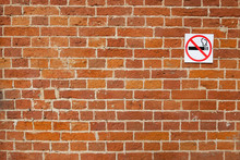 Three- Dimensional Elements Of Brickwork On The Wall. Terraces On An Old Brick Wall. Old Weathered Red Brick. No Smoking Sign On The Brick Wall.