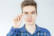 © alexander132 - Young man in blue shirt and glasses on light grey background. Man holding glasses
