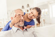 © Westend61 - Happy girl covering father's eyes on couch in living room