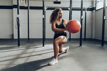 Young Woman Exercising  With Medicine Ball In Gym
