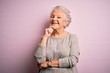 Senior beautiful woman wearing casual t-shirt standing over isolated pink background looking confident at the camera smiling with crossed arms and hand raised on chin. Thinking positive.