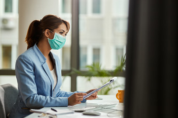 Wall Mural - Businesswoman wearing face mask while analzying reports in the office.