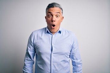 Poster - Middle age handsome grey-haired business man wearing elegant shirt over white background afraid and shocked with surprise expression, fear and excited face.