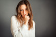 © maxfotoadobe - Young smiling girl in a white shirt hand near the mouth, the second in the pocket, tousled hair, isolator on a gray background. No retouching. Without makeup.