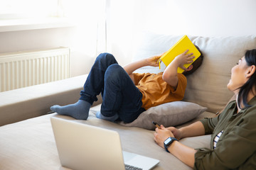 Wall Mural - Charming lady looking at son while he covering face with book