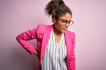 Poster - Beautiful african american businesswoman wearing jacket and glasses over pink background Suffering of backache, touching back with hand, muscular pain