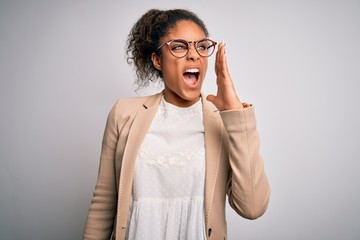 Sticker - Beautiful african american businesswoman wearing jacket and glasses over white background shouting and screaming loud to side with hand on mouth. Communication concept.