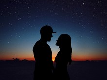 Silhouette Romantic Couple Standing Face To Face On Field Against Star Field