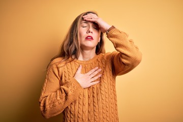 Canvas Print - Young beautiful blonde woman wearing casual sweater standing over yellow background Touching forehead for illness and fever, flu and cold, virus sick