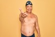 © Krakenimages.com - Middle age senior grey-haired swimmer man wearing swimsuit, cap and goggles smiling cheerful offering palm hand giving assistance and acceptance.