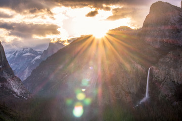 Sun rising above Sentinel Dome, casting golden light on Yosemite Valley and Bridalveil Falls. A huge sun burst and lens flare caused as the sun breaks the horizon. 