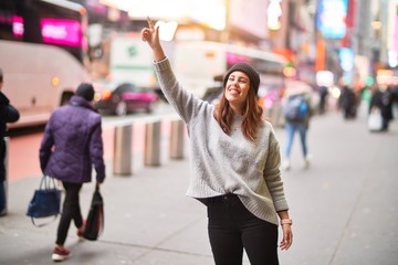 Young beautiful woman smiling happy and confident. Standing with smile on face and hand up calling cab at the city