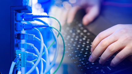 Remote work of a technical specialist. Work as a freelance programmer. A person is working at a computer against the background of connected wires. The man is engaged in computer networks.