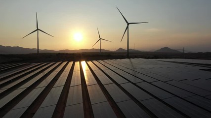 windmill and solar panel produces green, environmentaly friendly energy from the setting sun. view f