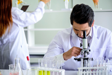 Wall Mural - attractive happiness scientist man lab technician assistant analyzing sample in test tube with micro